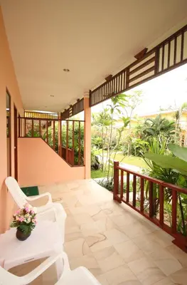 a room with a balcony with white chairs and a table at Bida Daree Resort in Ao Nang Beach