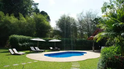 a swimming pool with two umbrellas and a fountain at Cliffside Lagoon Villa in Ao Nang Beach