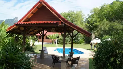 a pavilion with a table and chairs next to a pool at Cliffside Lagoon Villa in Ao Nang Beach