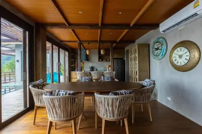 a dining room with a table and chairs and a clock at \u67e5\u9f993\u5367\u5ba4\u534a\u5c71\u6d77\u666f\u522b\u5885 in Ban Na Kok
