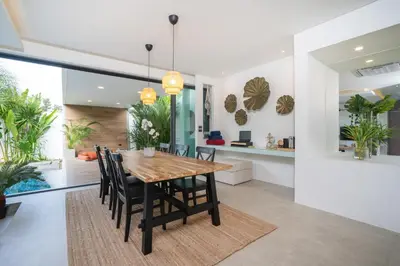 a dining room with a wooden table and chairs at Villa Kalliste Phuket - Lush Garden Escape in Nai Yang Beach