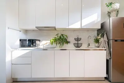 a white kitchen with white cabinets and plants at Villa Kalliste Phuket - Lush Garden Escape in Nai Yang Beach