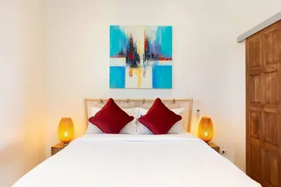 a bedroom with a white bed with two red pillows at V270 Best View In Phuket Hot Tub Great Location in Rawai Beach