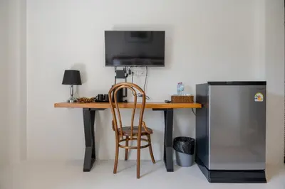 a desk with a television and a chair next to a refrigerator at Uncle Toy in Ban Riang