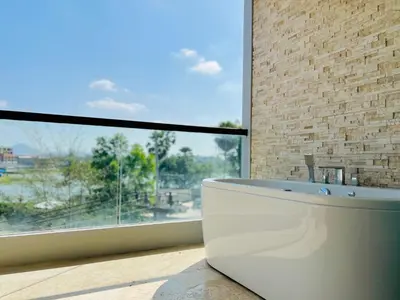 a bathroom with a tub in front of a large window at The Regent Bangtao by RESAVA in Bang Tao Beach
