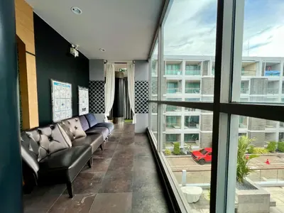 a living room with a couch and large windows at The Regent Bangtao by RESAVA in Bang Tao Beach