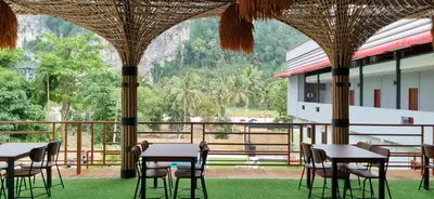 a restaurant with tables and chairs and a balcony at Fahsai Hostel in Ao Nang Beach