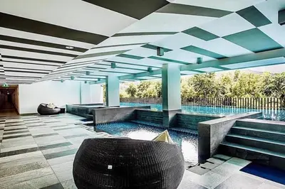 a swimming pool with a chair in the middle of a building at Stylish condo near Boat Avenue LAGUNA in Bang Tao Beach