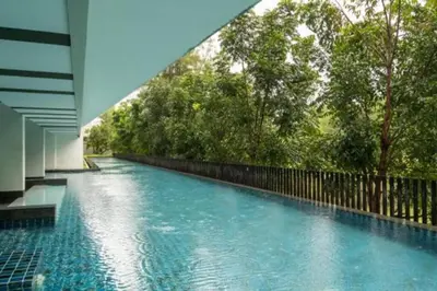 a swimming pool with blue water and trees at Stylish condo near Boat Avenue LAGUNA in Bang Tao Beach