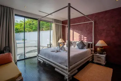 a bedroom with a canopy bed and a balcony at Naiharn Pool Villa Number 5 in Rawai Beach