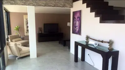 a living room with a staircase and a table and chair at Villa Patong in Patong Beach