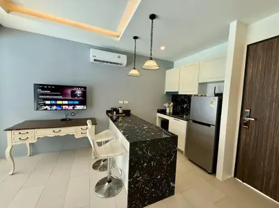 a kitchen with a desk and a refrigerator at Poolside 1 Bedroom Apartment by Renttini in Surin Beach