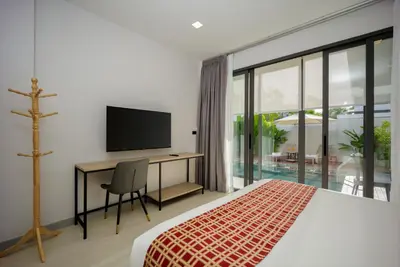 a bedroom with a bed and a desk with a television at Barringtonia pool villa in Phuket Town
