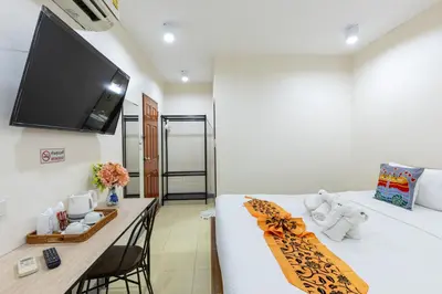 a room with a bed with a desk and a flat screen tv at PMS Boutique Patong in Patong Beach