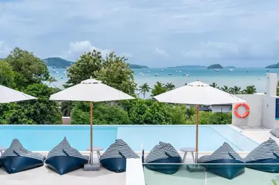 a pool with umbrellas and chairs next to a swimming pool at Chalong Marina Bay View Phuket in Rawai Beach