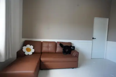 a brown leather couch with a black dog sitting on it at Hommory Residence - East Chalong in Phuket Town
