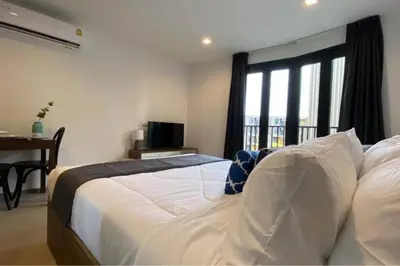 a bedroom with a bed and a desk and a window at Mode apartment central Phuket in Phuket Town