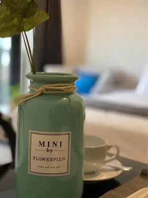 a green jar with a plant in it on a table at Mode apartment central Phuket in Phuket Town