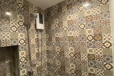 a bathroom with a shower with a tiled wall at Mode apartment central Phuket in Phuket Town
