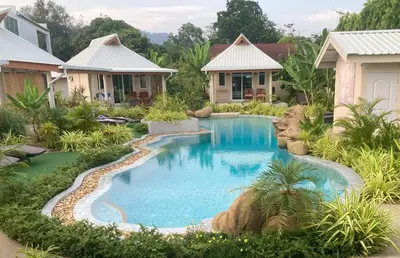 a swimming pool in a yard with houses at The Hidden Lagoon Resort - Exclusively for Adults in Rawai Beach