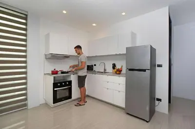 a man standing in a kitchen preparing food at Lively Stay at Vibrant Kata, 4BR Pool Villa B2 near Beach - UTK2 in Kata Beach