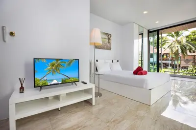 a white bedroom with a bed and a tv at Lively Stay at Vibrant Kata, 4BR Pool Villa B2 near Beach - UTK2 in Kata Beach