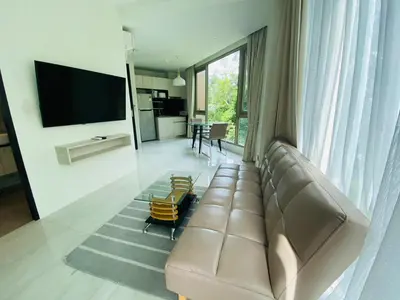 a living room with a leather couch and a television at A26 Oceana Kamala in Kamala Beach