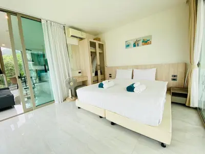 a bedroom with a large white bed and glass doors at A45 Oceana Kamala in Kamala Beach