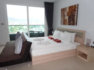 a bedroom with a large bed and a chair at Private sea view apartment at Emerald Terrace in Patong Beach