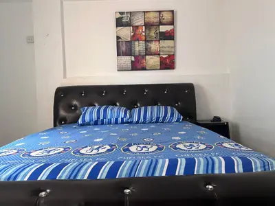 a bed with a blue comforter and two pillows at KC Kamala Guesthouse in Kamala Beach