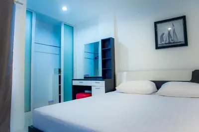a bedroom with a white bed and a mirror at KC Kamala Guesthouse in Kamala Beach