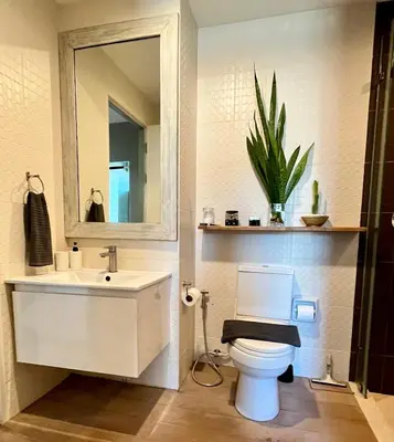 a bathroom with a toilet and a sink and a mirror at ZcapeX2 condominium in Bang Tao Beach
