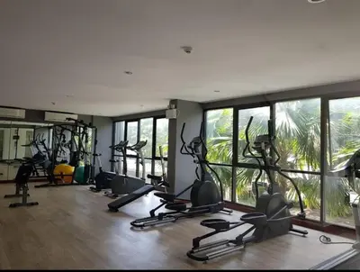 a gym with several treadmills and ellipticals in a room with windows at ZcapeX2 condominium in Bang Tao Beach