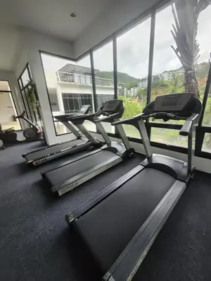 a gym with three treadmills in front of a large window at Veloche Karon palm in Phuket Town