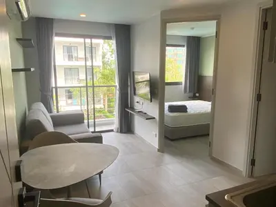 a living room with a table and a room with a bed at CondoHotel Chalong in Ban Klang