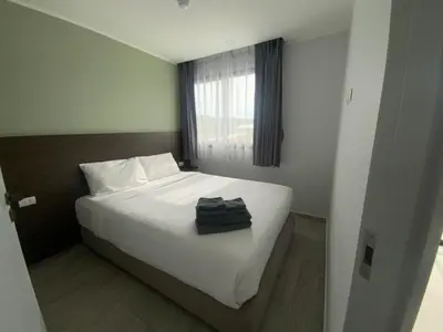 a bedroom with a white bed and a window at CondoHotel Chalong in Ban Klang