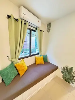 a window seat in a room with yellow and green pillows at Pupa Rooms in Patong Beach