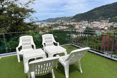 three white chairs sitting on a balcony with a view at JZ Patong in Patong Beach