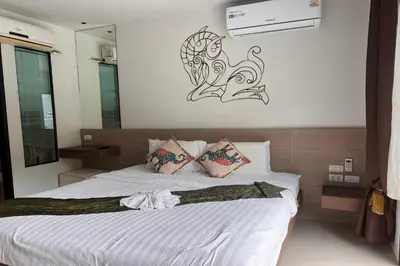 a bedroom with a white bed with a painting on the wall at JZ Patong in Patong Beach