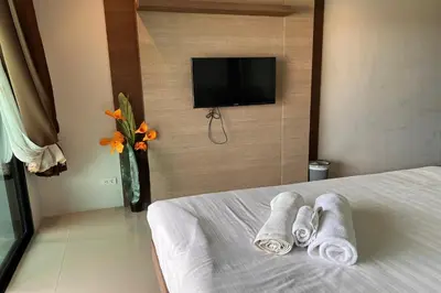 a hotel room with towels on a bed with a tv at JZ Patong in Patong Beach