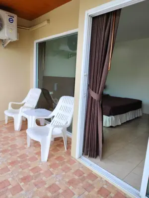 a balcony with two white chairs and a bed at Baan Thawin in Patong Beach