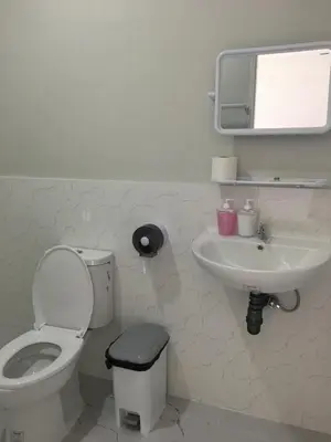 a white bathroom with a toilet and a sink at Sunshine guesthouse in Ban Saiyuan (1)