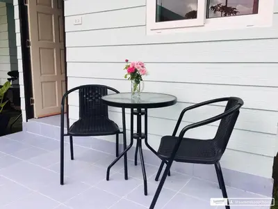 a table and two chairs and a vase of flowers on a patio at Sunshine guesthouse in Ban Saiyuan (1)