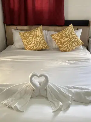 two white swans forming a heart on a bed at Sunshine guesthouse in Ban Saiyuan (1)