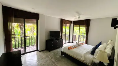 a bedroom with a bed and a tv and windows at 23 - Seaside Villa Retreat in Phuket Town