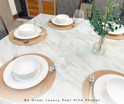 a white table with plates and wine glasses on it at Luxury Pool Villa 5 mins to Phuket Old Town in Ban Lo Long