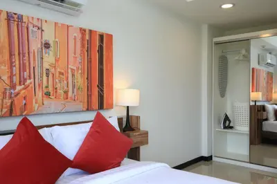 a bedroom with red pillows and a painting on the wall at MBC by Capital Pro in Mai Khao Beach