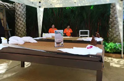 a table with two people in the background with a bed at MBC by Capital Pro in Mai Khao Beach