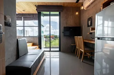a living room with a couch and a kitchen with a table at Studio Sora Rooftop Pool ReLife Nai Harn Beach in Rawai Beach