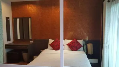 a bed with red pillows in a bedroom with a mirror at Phuket Villa Patong in Patong Beach